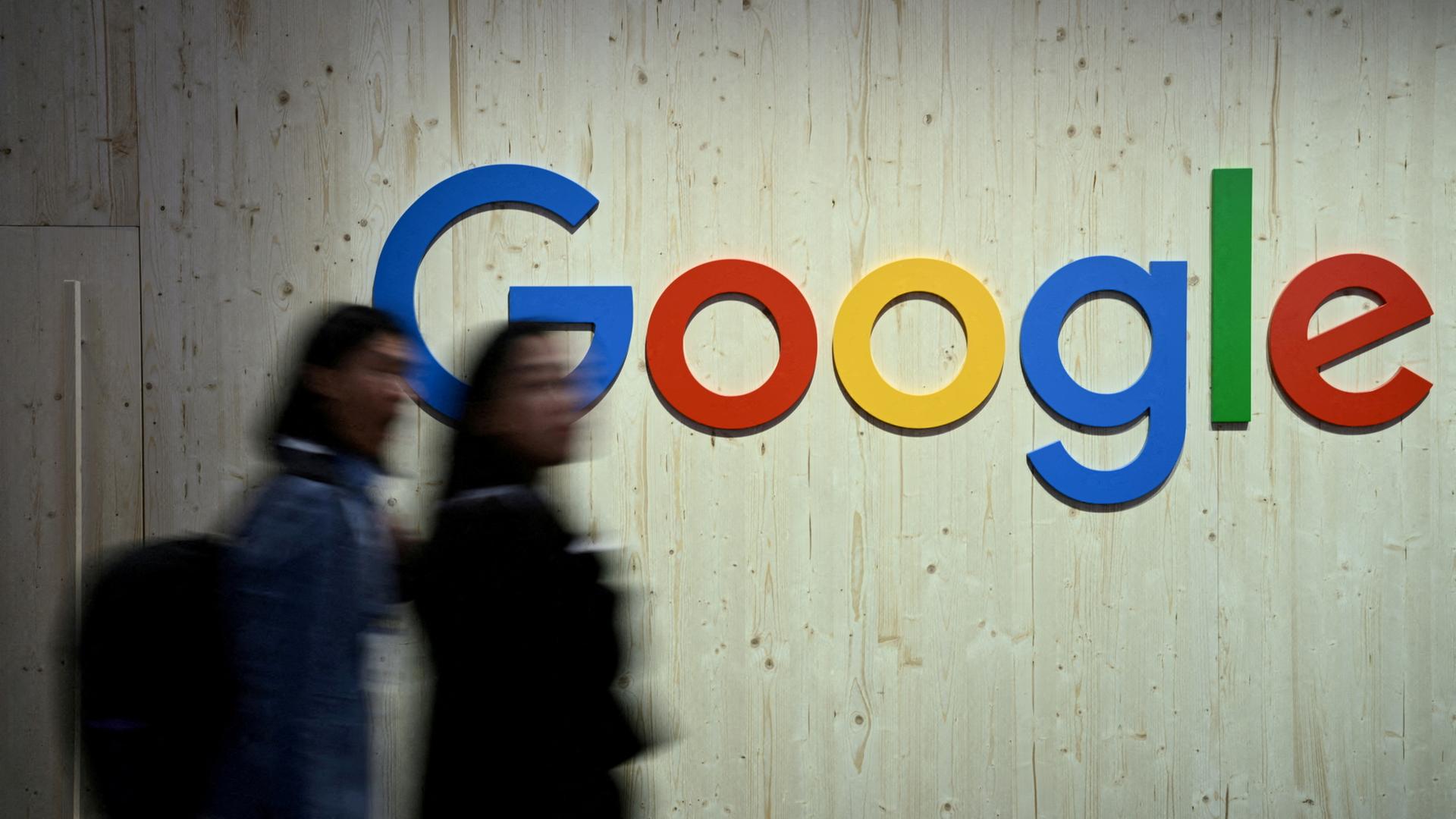 Menschen laufen an einem Google-Logo vorbei. | REUTERS
