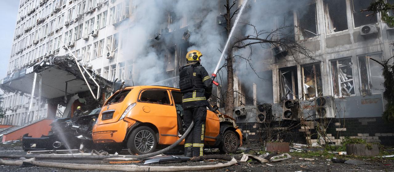 Ein Feuerwehrmann löscht in Kiew (Ukraine) einen Brand in einem brennenden Gebäude.