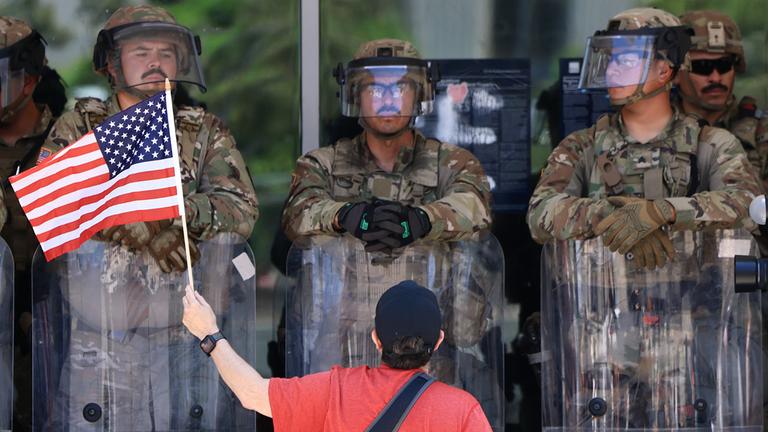 Ein Demonstrant mit einer US-Flagge steht vor US-Marines in Los Angeles.