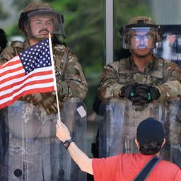 Ein Demonstrant mit einer US-Flagge steht vor US-Marines in Los Angeles.