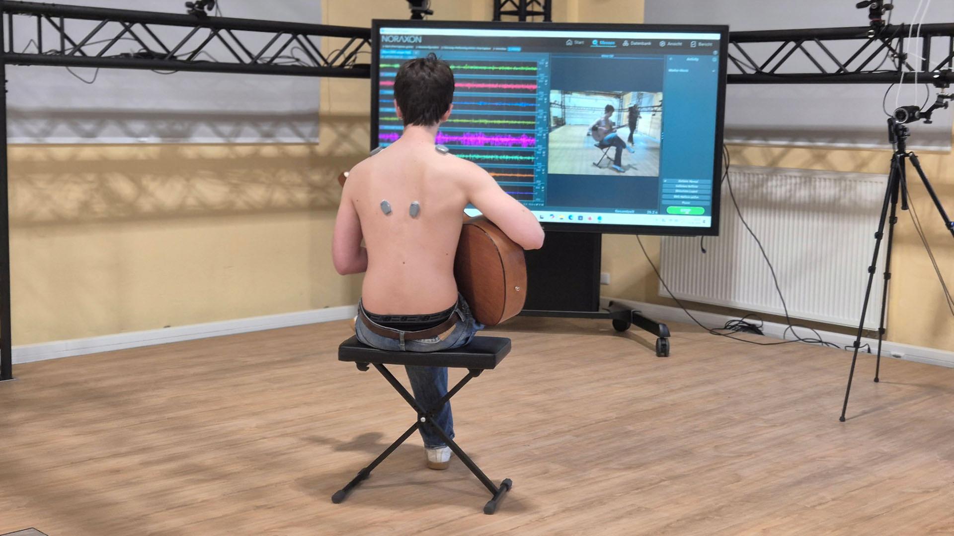 Ein Mann mit einer Gitarre vor einem Monitor. | Britta Nareyka, NDR