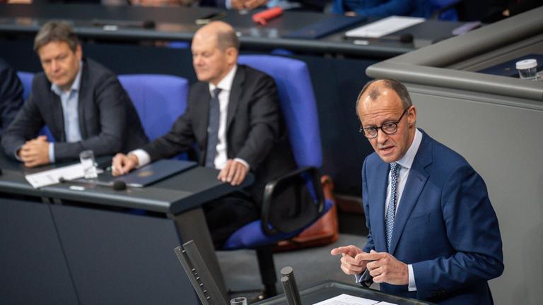 Friedrich Merz (r-l) spricht vor Olaf Scholz und Robert Habeck im Bundestag.