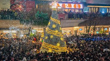Chinesen stehen am 24. Dezember rund um einen Christbaum mit künstlichem Schnee