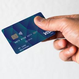 Ein Geflüchteter hält eine Debitkarte in der Hand.