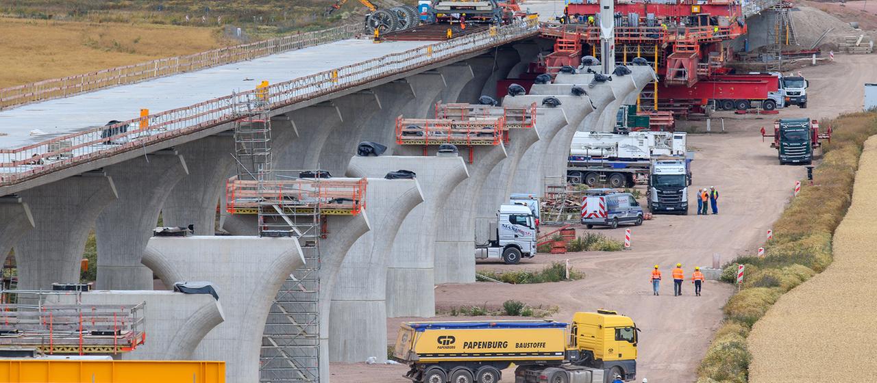 Arbeiter gehen auf der Baustelle der Saalebrücke an der Vorlandbrücke in Sachsen-Anhalt vorbei. 