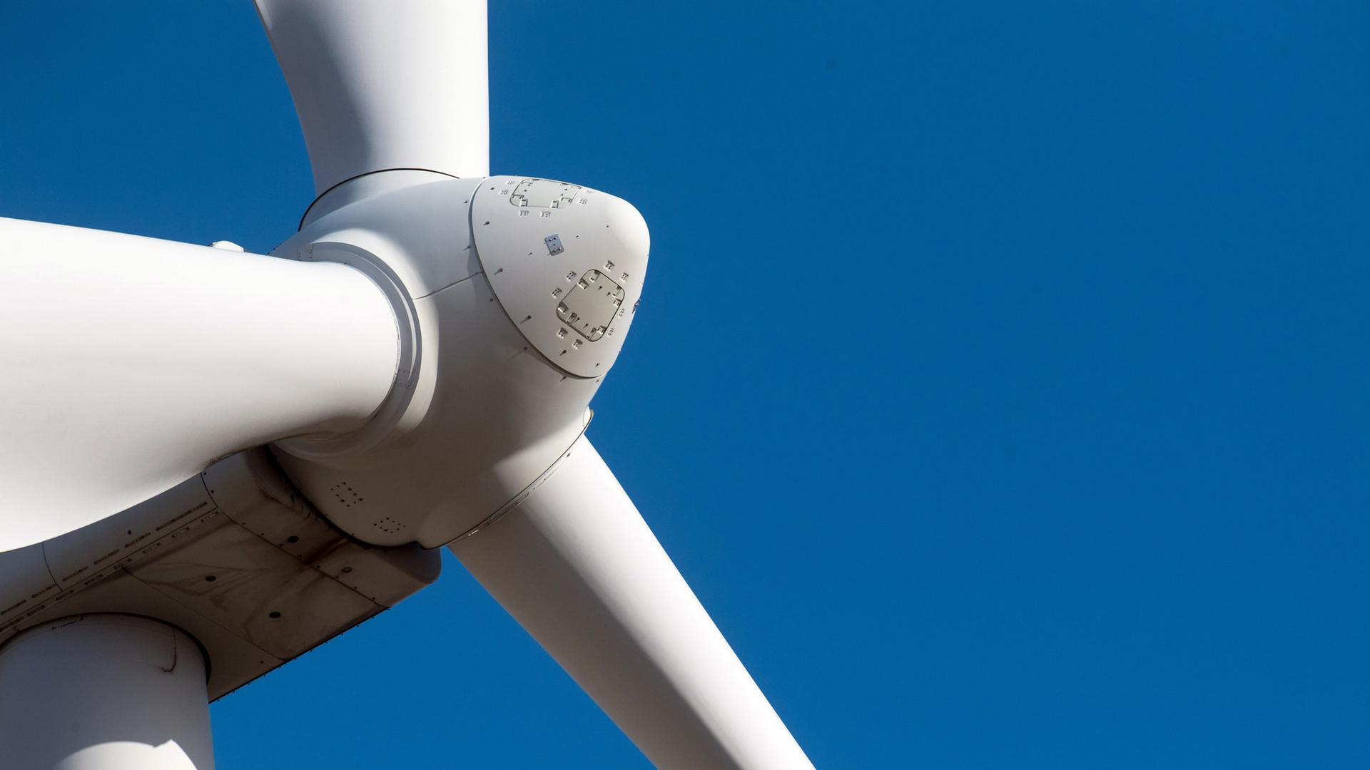 Detailaufnahme der Rotornabe und zweier Rotorblätter einer Windkraftanlage aus der Untersicht. Die weißen Bauteile heben sich vor einem klaren, wolkenlosen blauen Himmel ab. | picture alliance/dpa/dpa-Zentralbild | Stefan Sauer