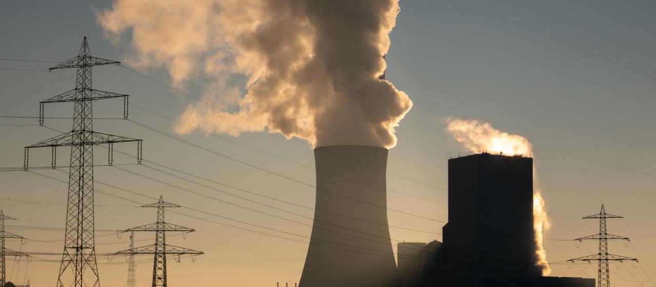 Die Sonne geht hinter einem Kohlekraftwerk auf. 