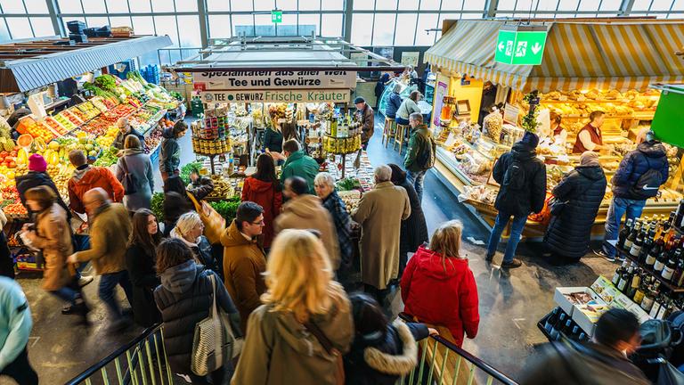 Menschen erledigen in der Kleinmarkthalle in Frankfurt/Main ihre Einkäufe.