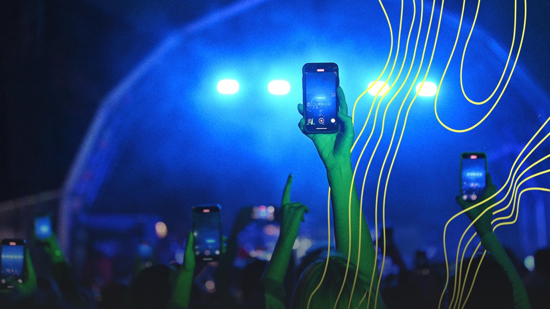 Eine Frau hält ihr Handy bei einem Konzert auf die Bühne. | picture alliance / SZ Photo, Robert Haas