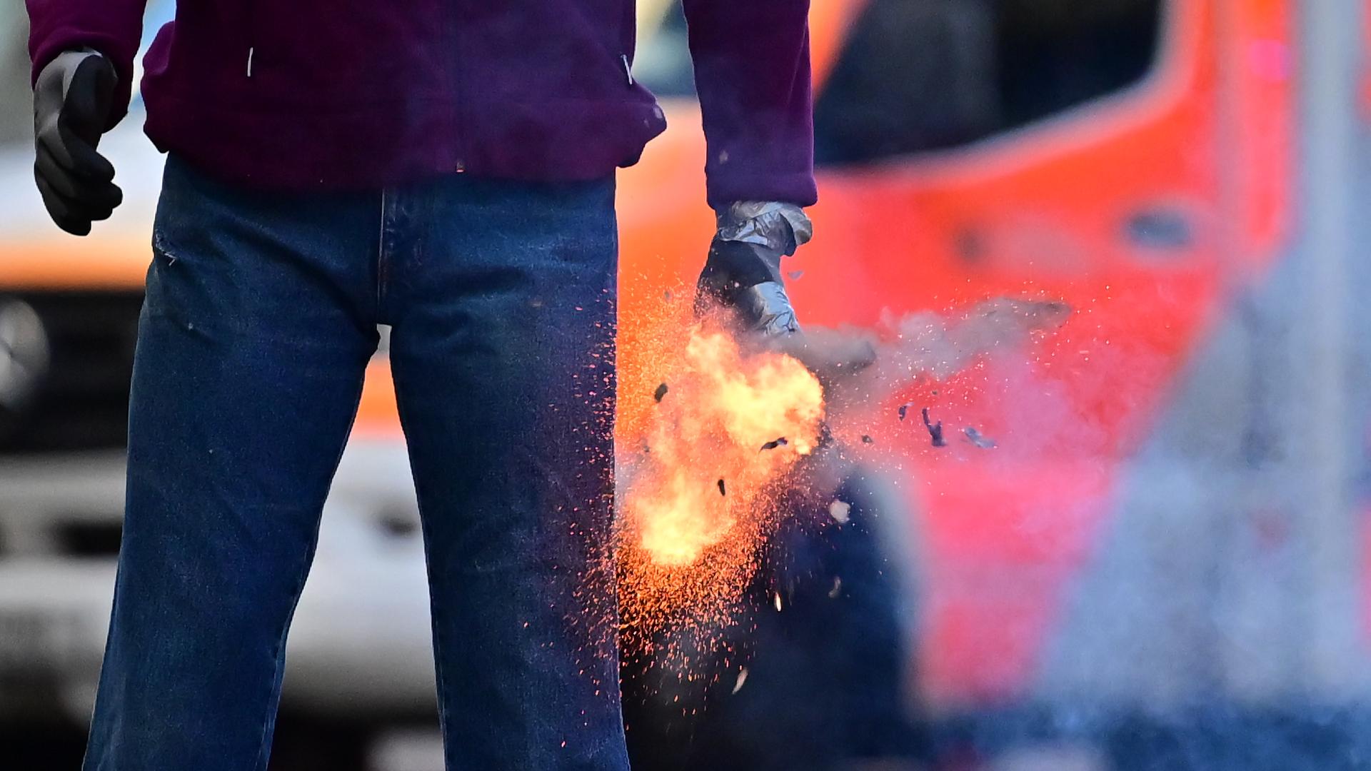 Mann mit Feuerwerksk�rper vor einem Rettungswagen | dpa