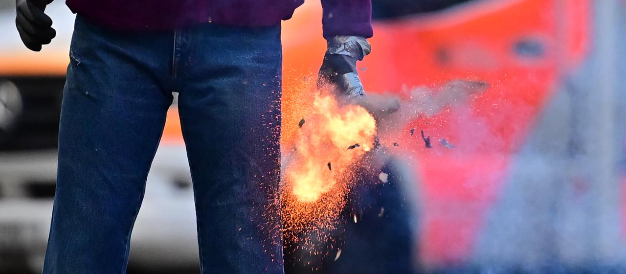 Mann mit Feuerwerkskörper vor einem Rettungswagen