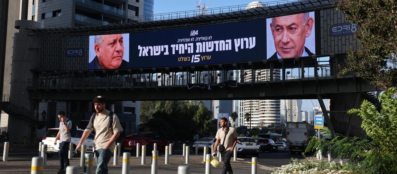 Menschen laufen im israelischen Tel Aviv an einer Wahlplakatwand vorbei.