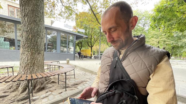 Oleh Wlasenko schaut auf sein Smartphone.
