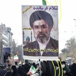 Ein Mann hält ein Poster hoch auf dem Mojtaba Khamenei zu sehen ist.