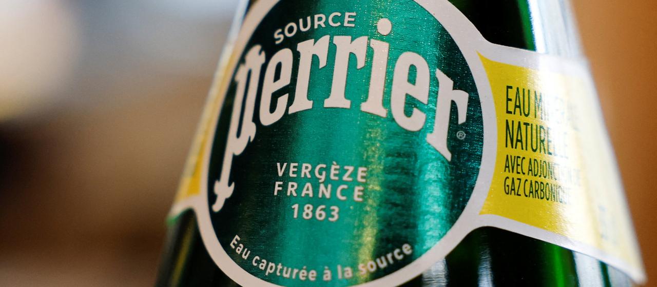 Eine Flasche Mineralwasser von Perrier steht auf einem Tisch.