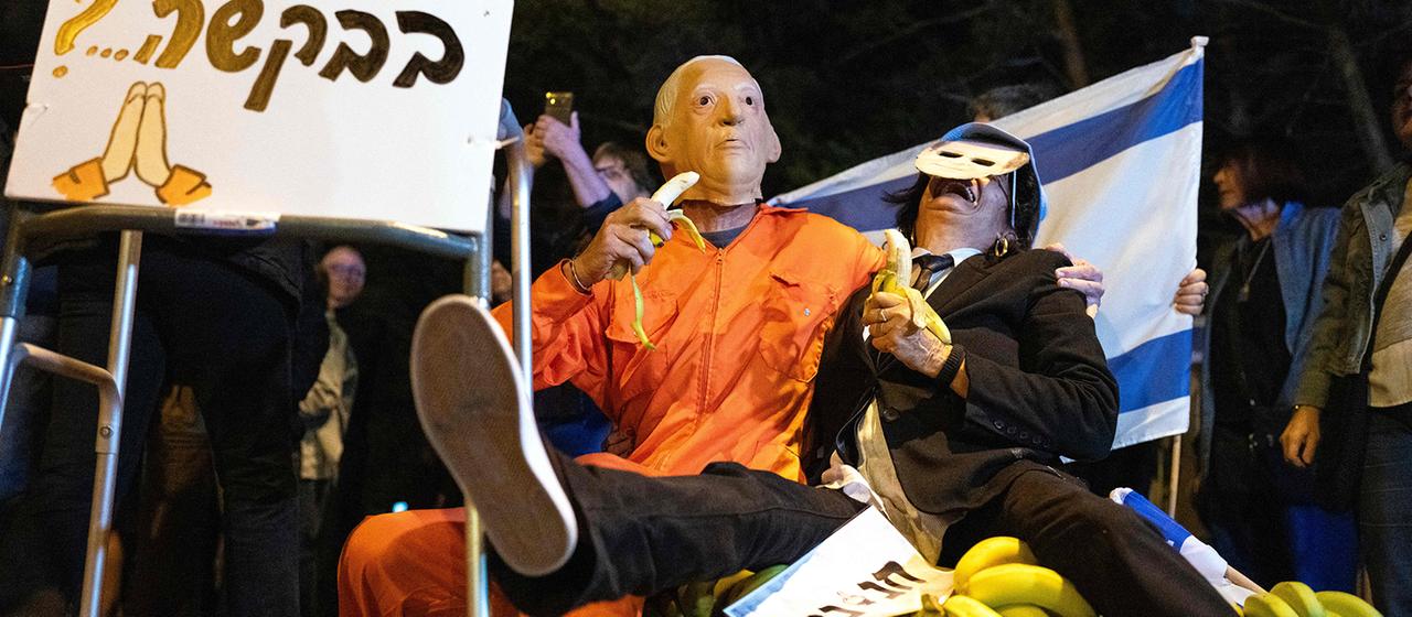 Proteste in Tel Aviv: verkleidete Demonstranten sitzen auf einem Haufen Bananen.