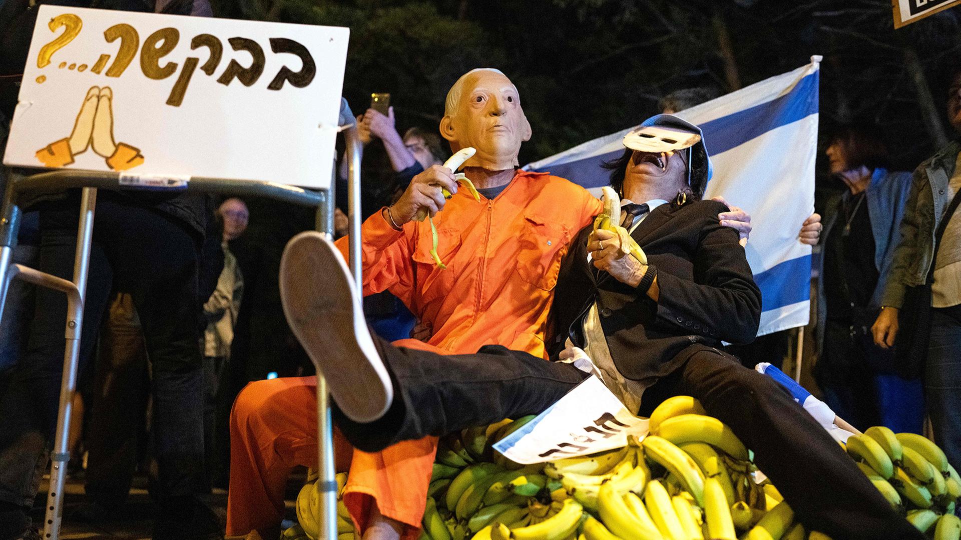 Proteste in Tel Aviv: verkleidete Demonstranten sitzen auf einem Haufen Bananen. | AFP