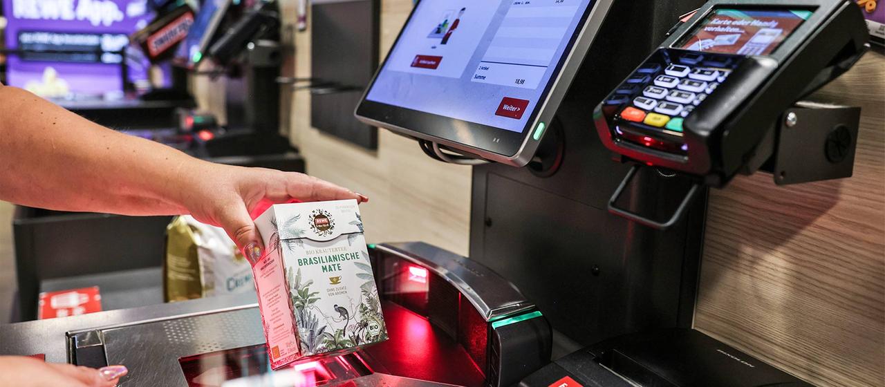 Eine Frau scannt ein Produkt an einer Selbstbedienungskasse in einem Supermarkt. | picture-alliance/dpa Eine Frau scannt ein Produkt an einer Selbstbedienungskasse in einem Supermarkt.