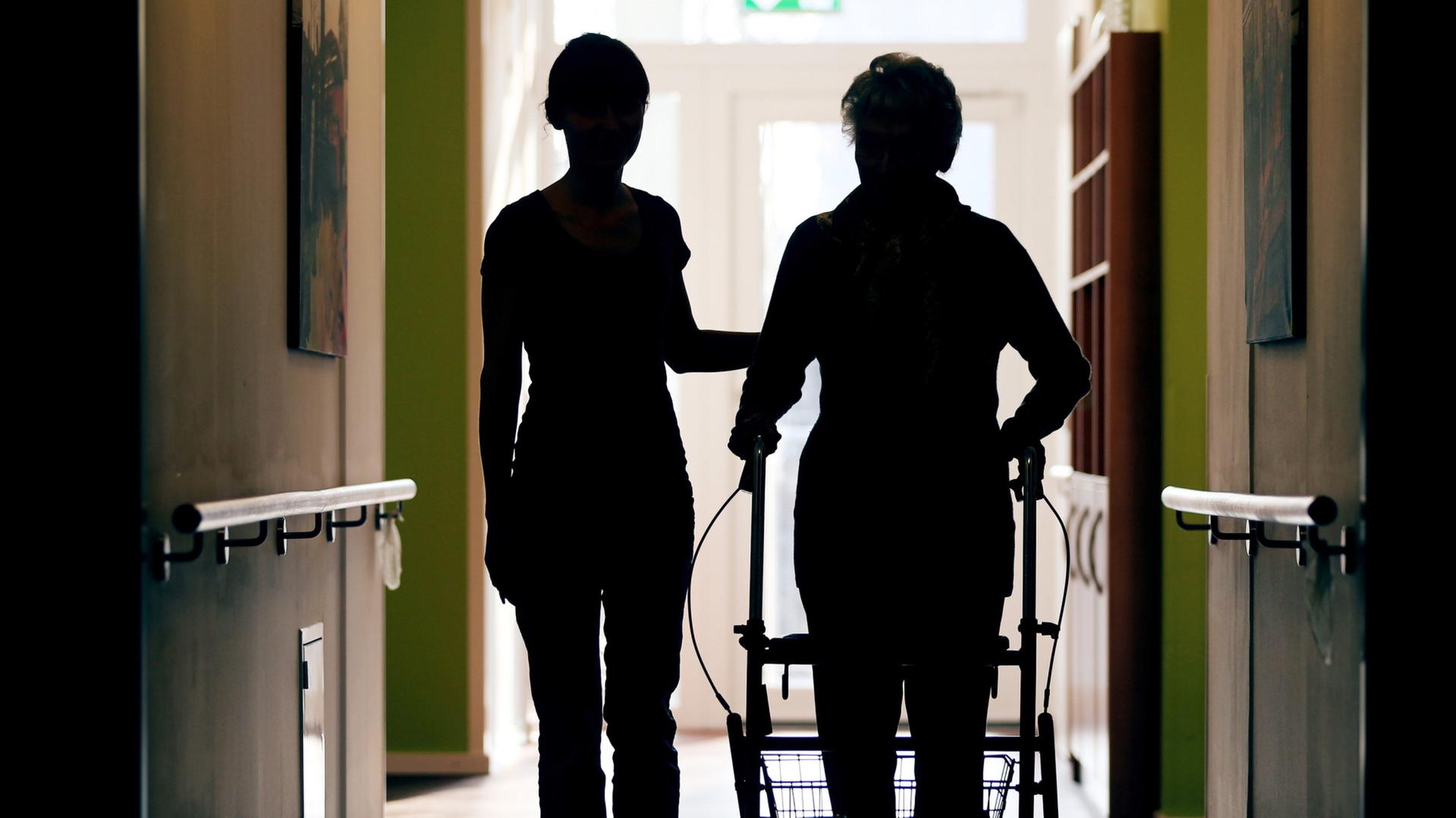 Eine Pflegekraft begleitet die Bewohnerin eines Altenheims | dpa