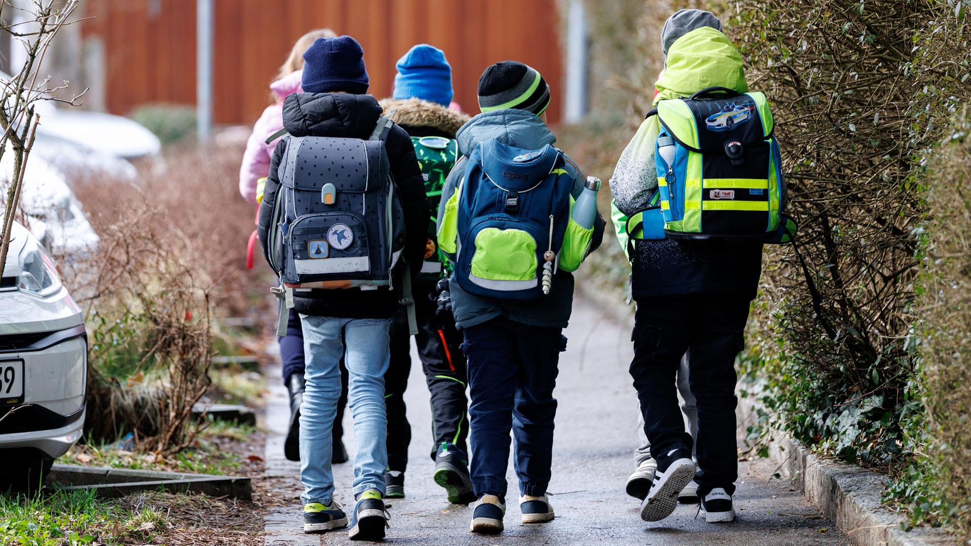 Schüler einer Grundschule gehen nach dem Unterrichtsende mit ihren Schulranzen auf dem Rücken einen Gehweg entlang. | picture alliance / dpa