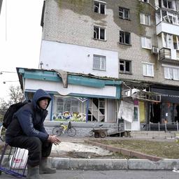  Menschen halten sich auf der Straße vor einem durch russischen Beschuss zerstörten Wohnhaus in Isjum (Ukraine) auf