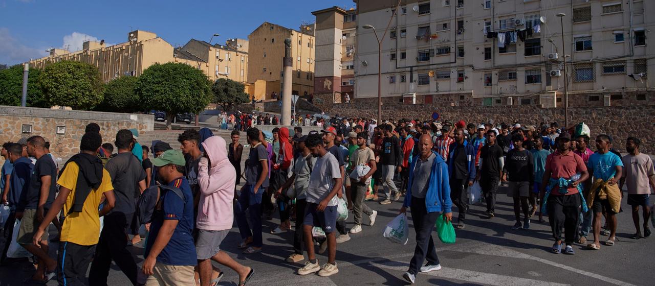 Migranten werden von der spanischen Polizei in Notunterkünfte in der spanischen Exklave Ceuta gebracht.