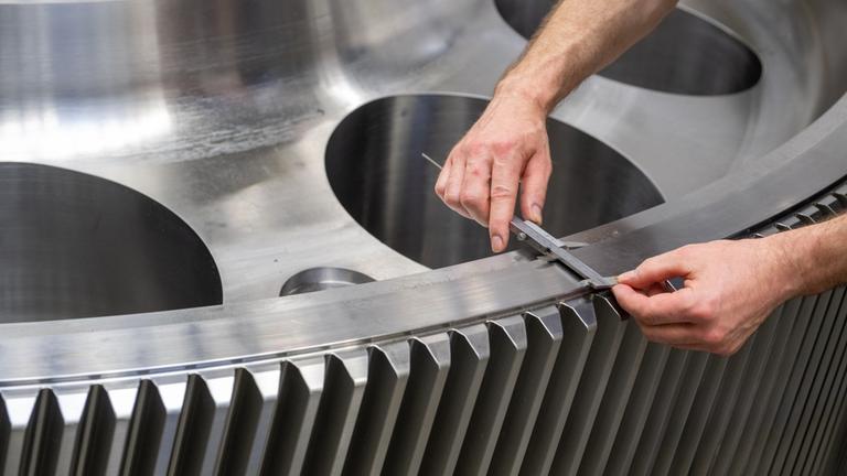 Ein Mitarbeiter der Firma Renk kontrolliert ein Getriebezahnrad.