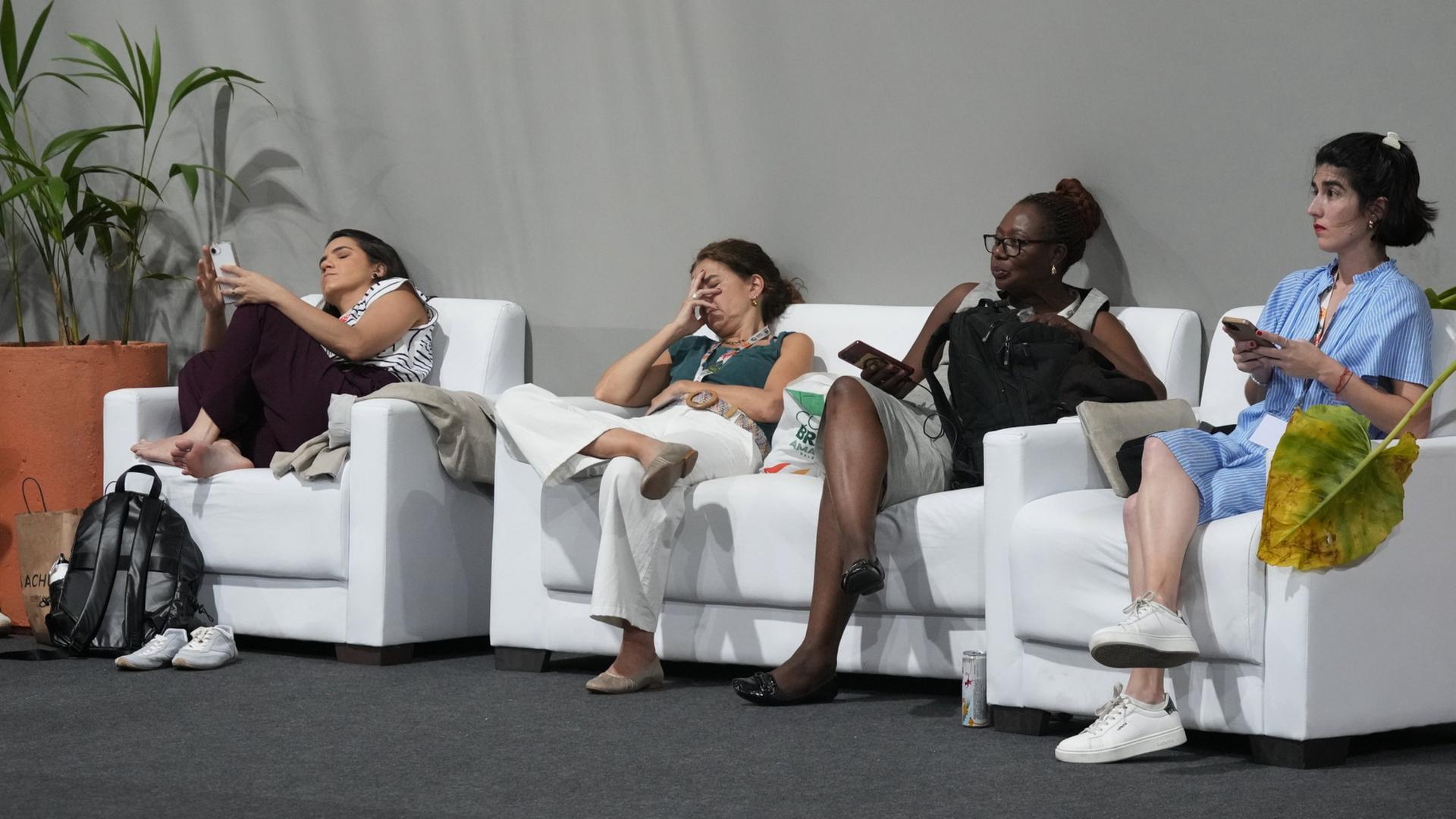 Teilnehmerinnen der Weltklimakonferenz ruhen sich auf Sesseln aus | AP