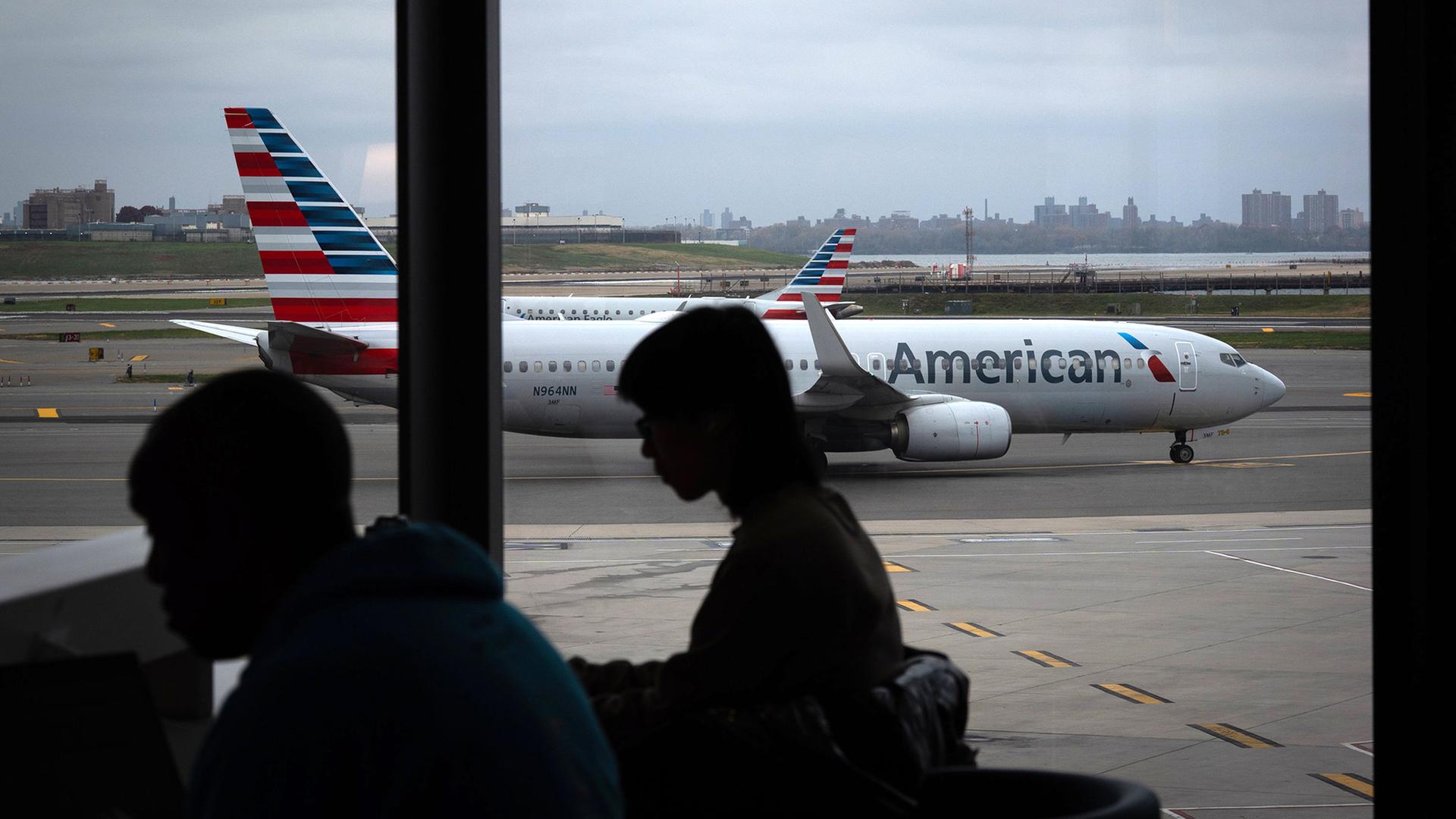 Menschen warten in einem Flughafen-Terminal. | AP