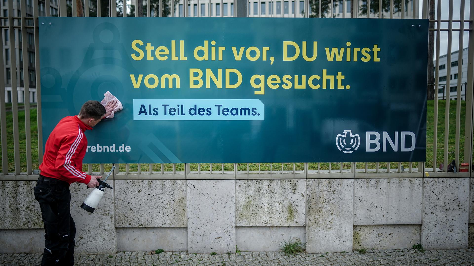 Ein Arbeiter subert ein Plakat der neuen Imagekampagne des Bundesnachrichtendienstes (BND) mit der Aufschrift 