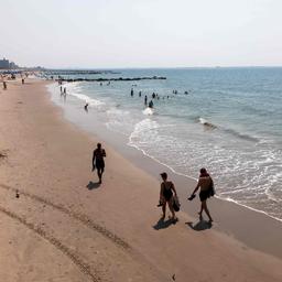 Menschen spazieren am Strand von Coney Island in Brooklyn in New York City entlang.