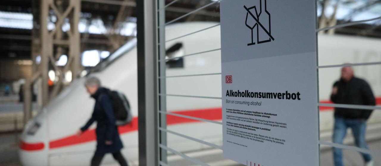 Ein Alkoholkonsumverbotsschild klebt an einem Glas in einem Bahnhof.