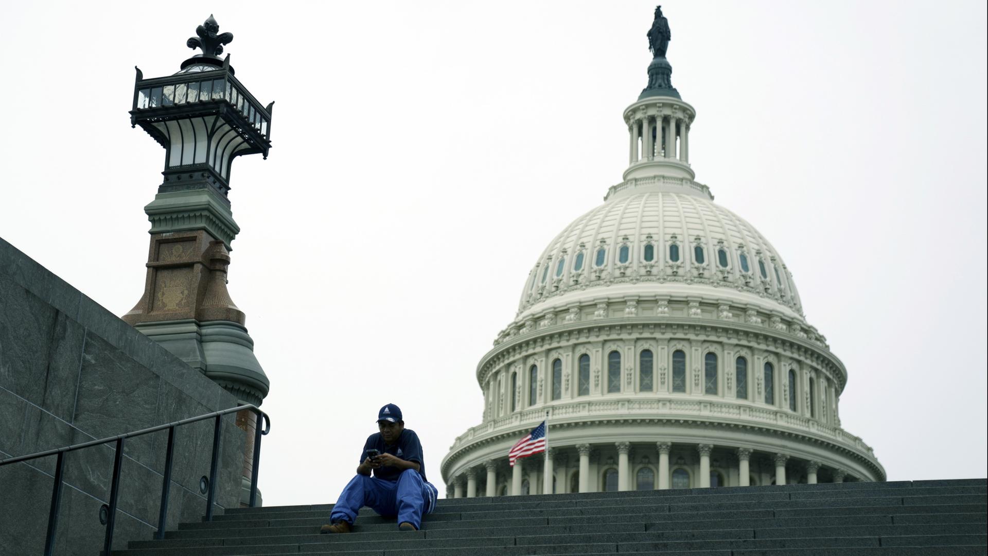 Eine Person sitzt auf den Stufen vor dem Kapitol in Washington | EPA