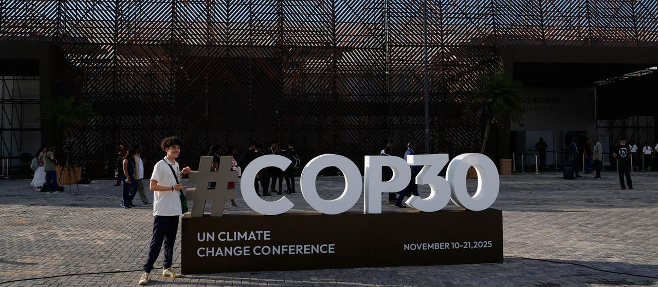 Eine Person posiert mit einem Schild für den UN-Klimagipfel COP30 in Belem, Brasilien. 
