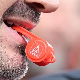 Nahaufnahme von einer Trillerpfeife im Mund eines Mannes. Auf der roten Trillerpfeife ist das IG-Metall-Logo abgebildet. Nach Streiks in der Metall- und Elektrobranche kam es nun zu einer Einigung.