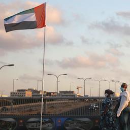 Frauen gehen auf der Friedensbrücke im israelischen Netanja an den Flaggen von Israel und den Vereinigten Arabischen Emiraten vorbei.