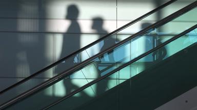 Schatten von Menschen hinter einer Rolltreppe