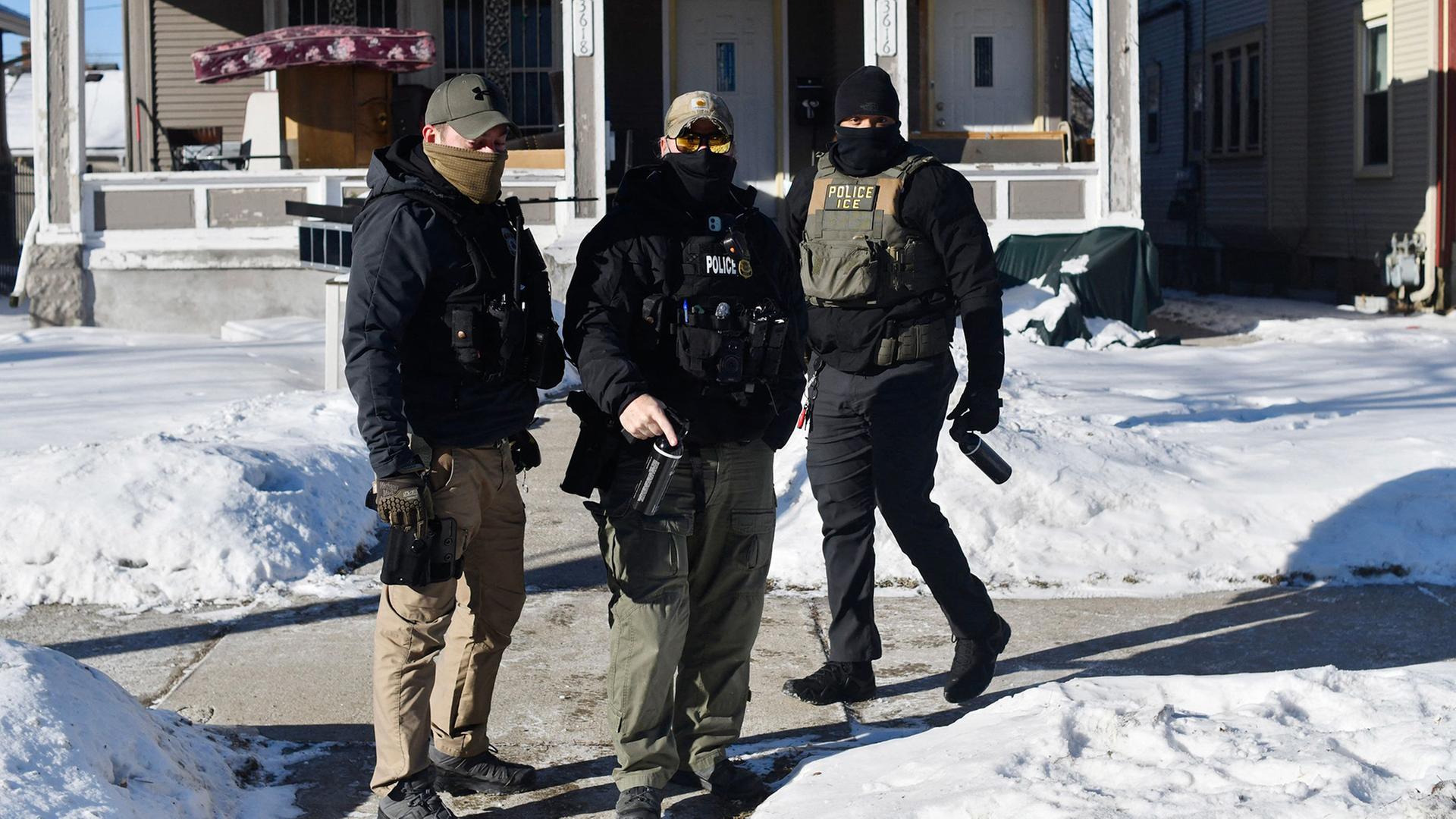 ICE-Einsatzkräfte mit Gesichtsmasken stehen vor einem Haus in Minneapolis (Minnesota). | AFP