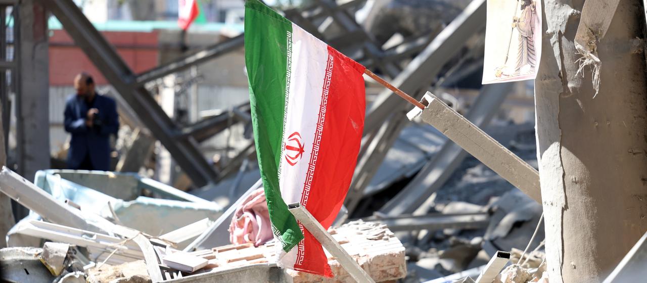 Auf Trümmern in Teheran weht eine iranische Flagge.