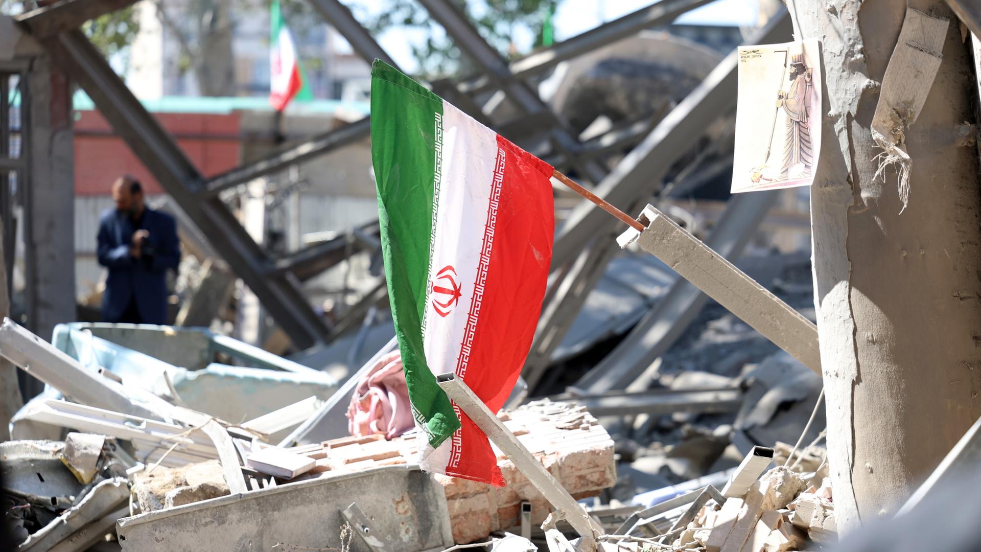 Auf Trümmern in Teheran weht eine iranische Flagge. | EPA
