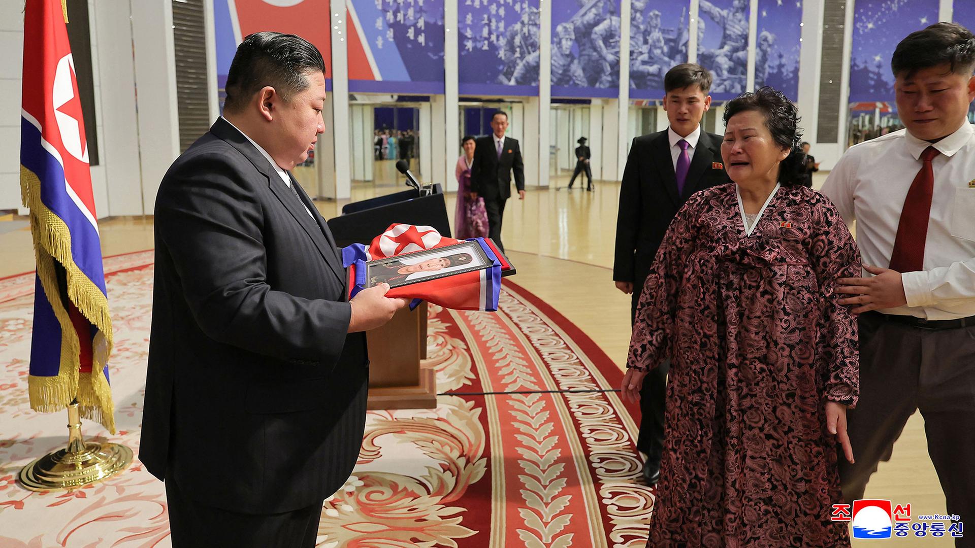 Kim Jong Un überreicht in Pjöngjang der Familie eines gefallenen Soldaten ein in die nordkoreanische Flagge gehülltes Porträt. | AFP PHOTO/KCNA VIA KNS