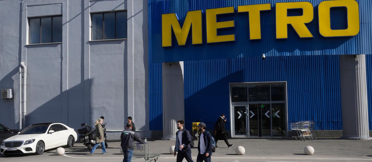 Menschen gehen vor einem Metro-Markt in Moskau entlang.