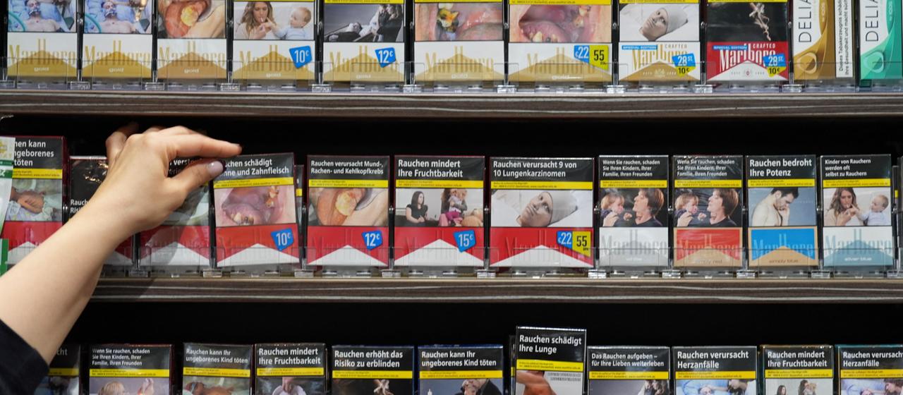 Eine Mitarbeiterin greift in einem Kiosk nach einer Packung Zigaretten.
