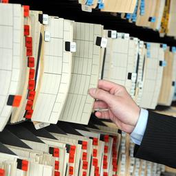 Ein Mann nimmt einen Aktenordner aus einem Regal.