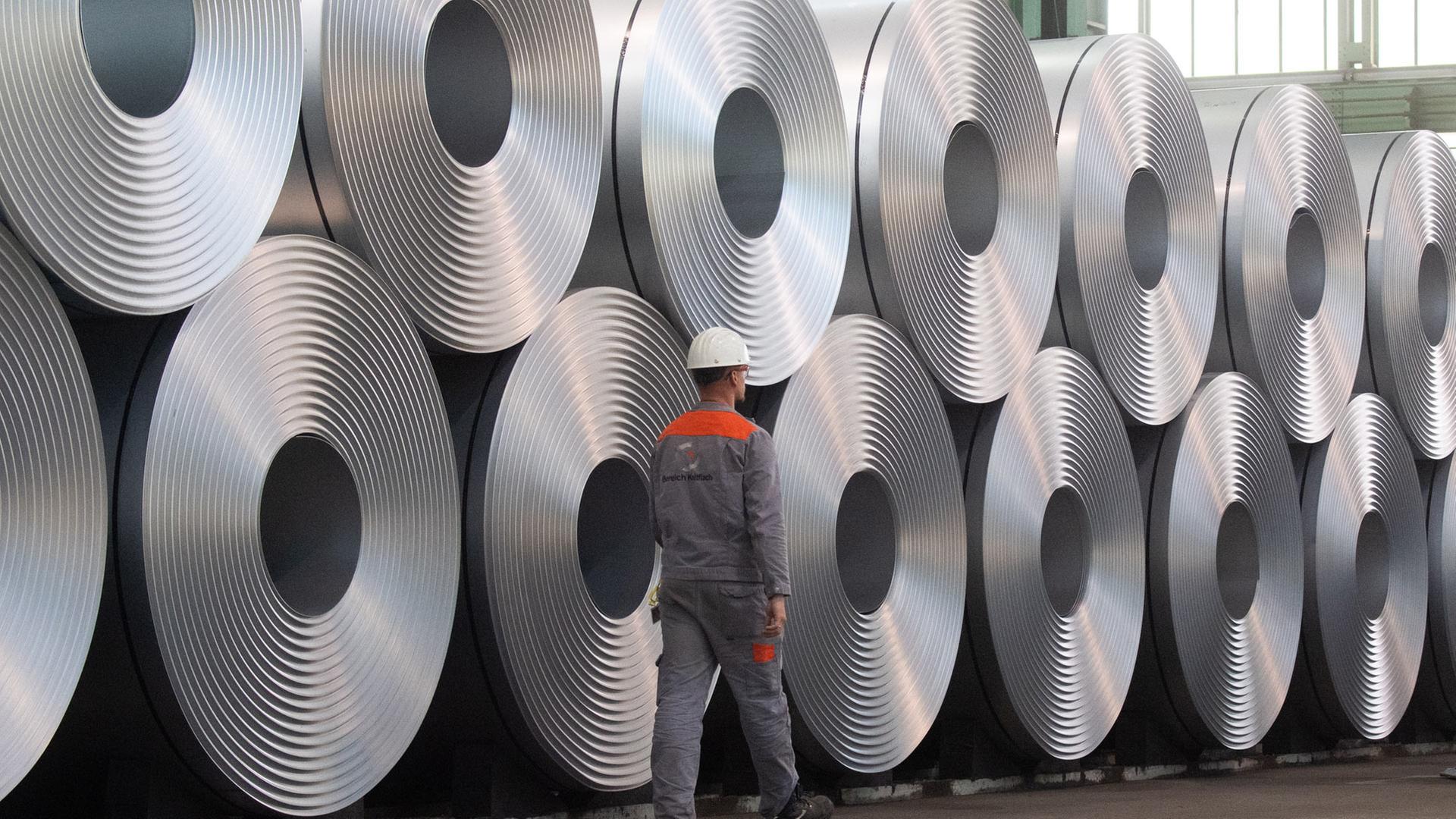 Eine Mitarbeiter geht bei der Salzgitter AG an aufgewickeltem Stahl (Coils) vorbei | picture alliance/dpa