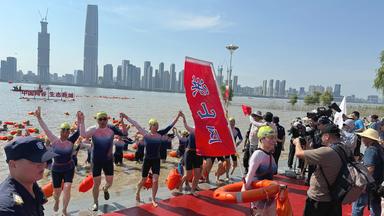 Menschen nach einem Bad im Yangtse vor der Skyline von Wuhan.