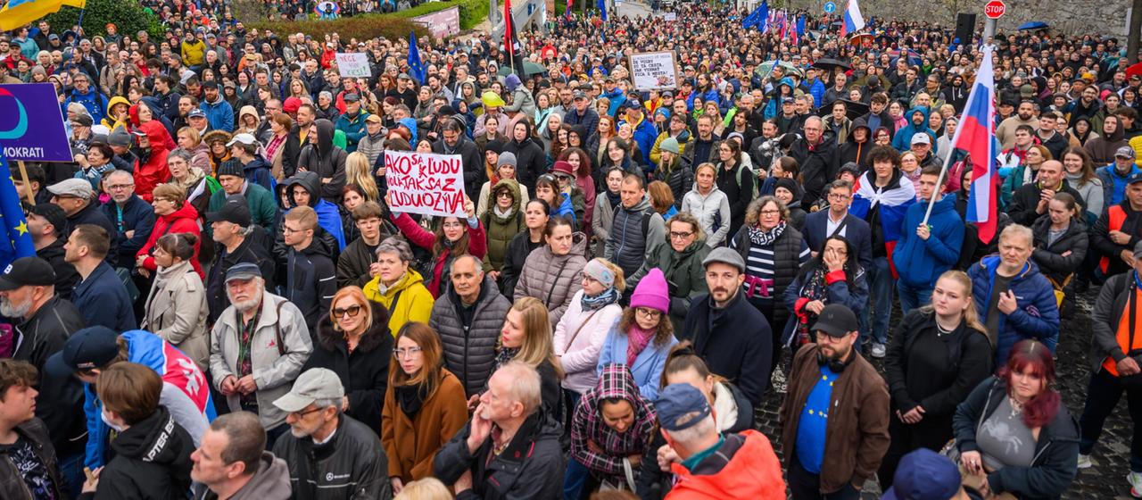 Tausende Menschen demonstrieren mit Fahnen und Plakaten.