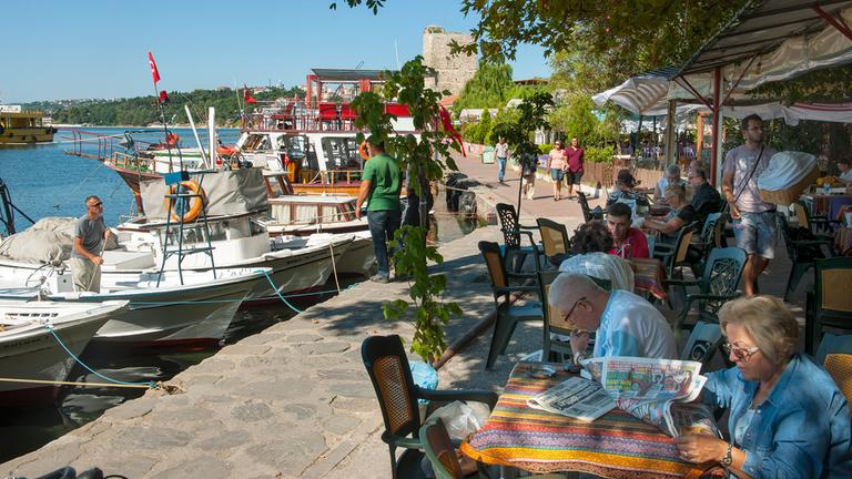 Menschen sitzen am Hafen von Sinop in einem Café.