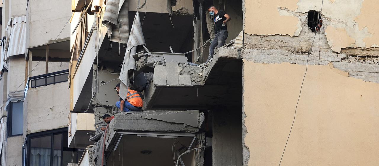 Zwei Männer begutachten massive Schäden an einem Wohnhaus.