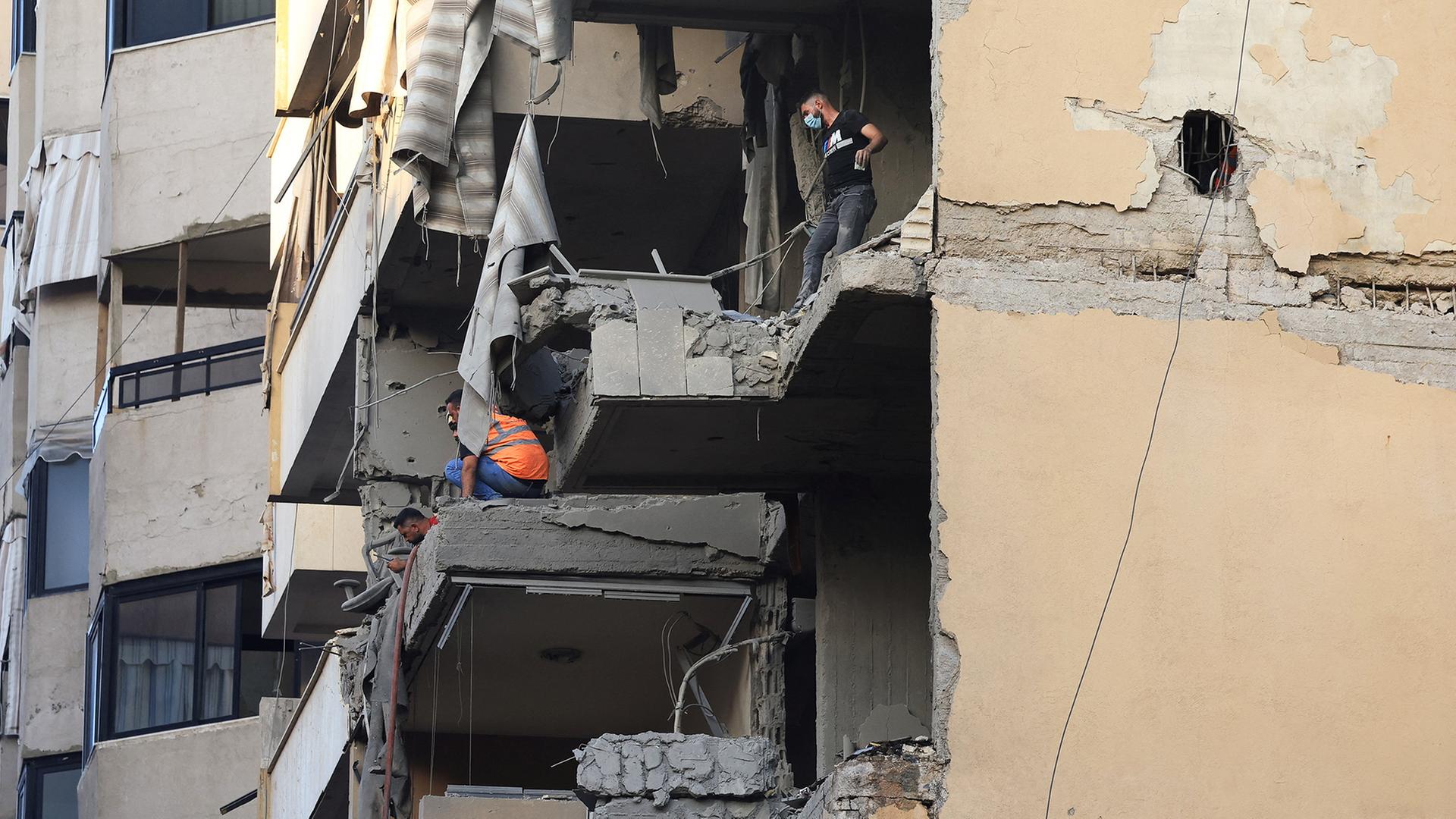 Zwei Männer begutachten massive Schäden an einem Wohnhaus. | REUTERS